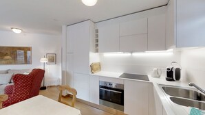 Een moderne keuken met witte kastjes, een inbouwoven, een koffiezetapparaat en een spoelbak.
