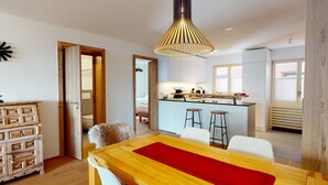 A modern kitchen with a central island, wooden furniture, and a pendant light.