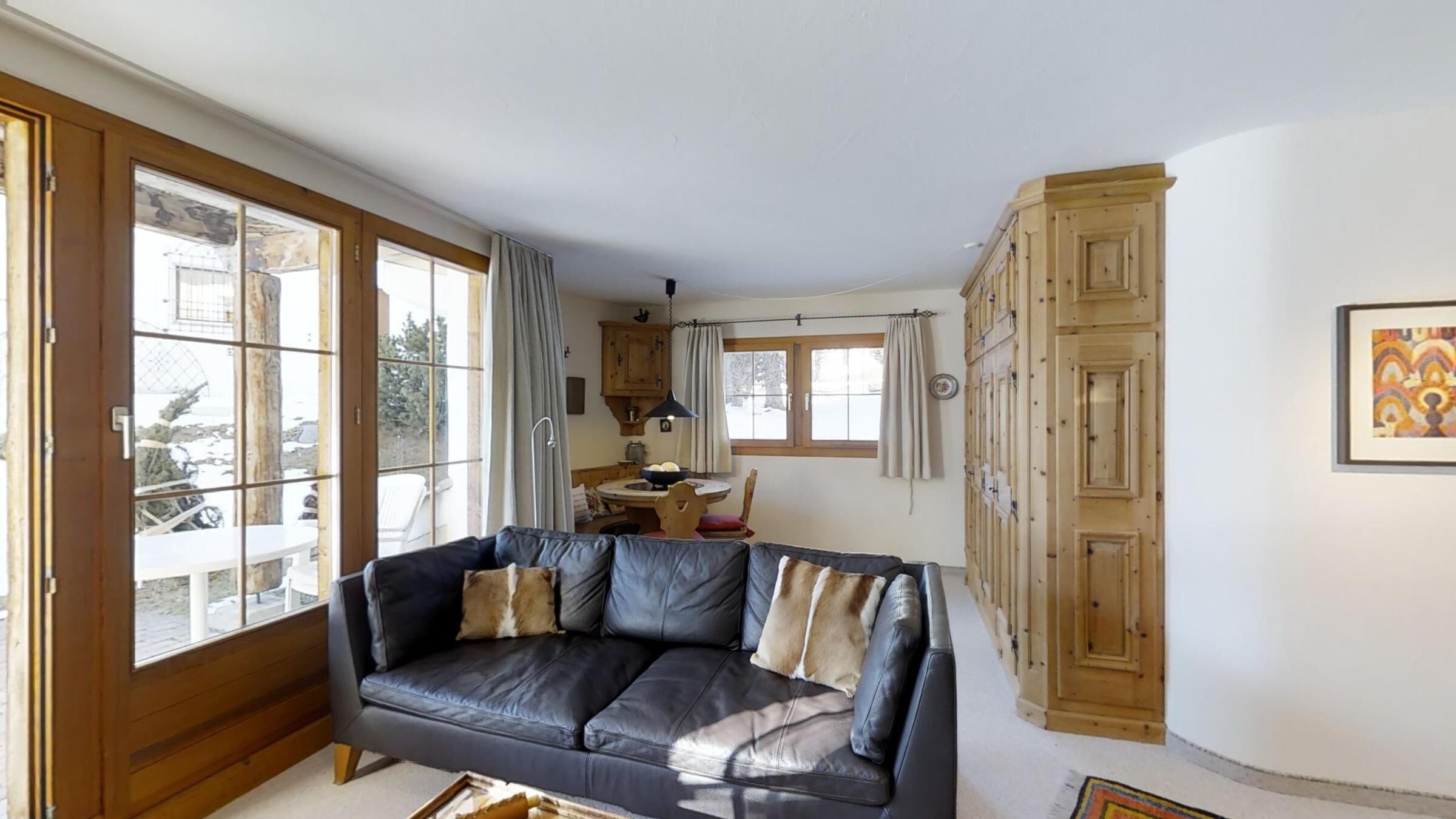 Un salon avec un canapé en cuir, des meubles en bois et un coin repas comprenant une table et des chaises.