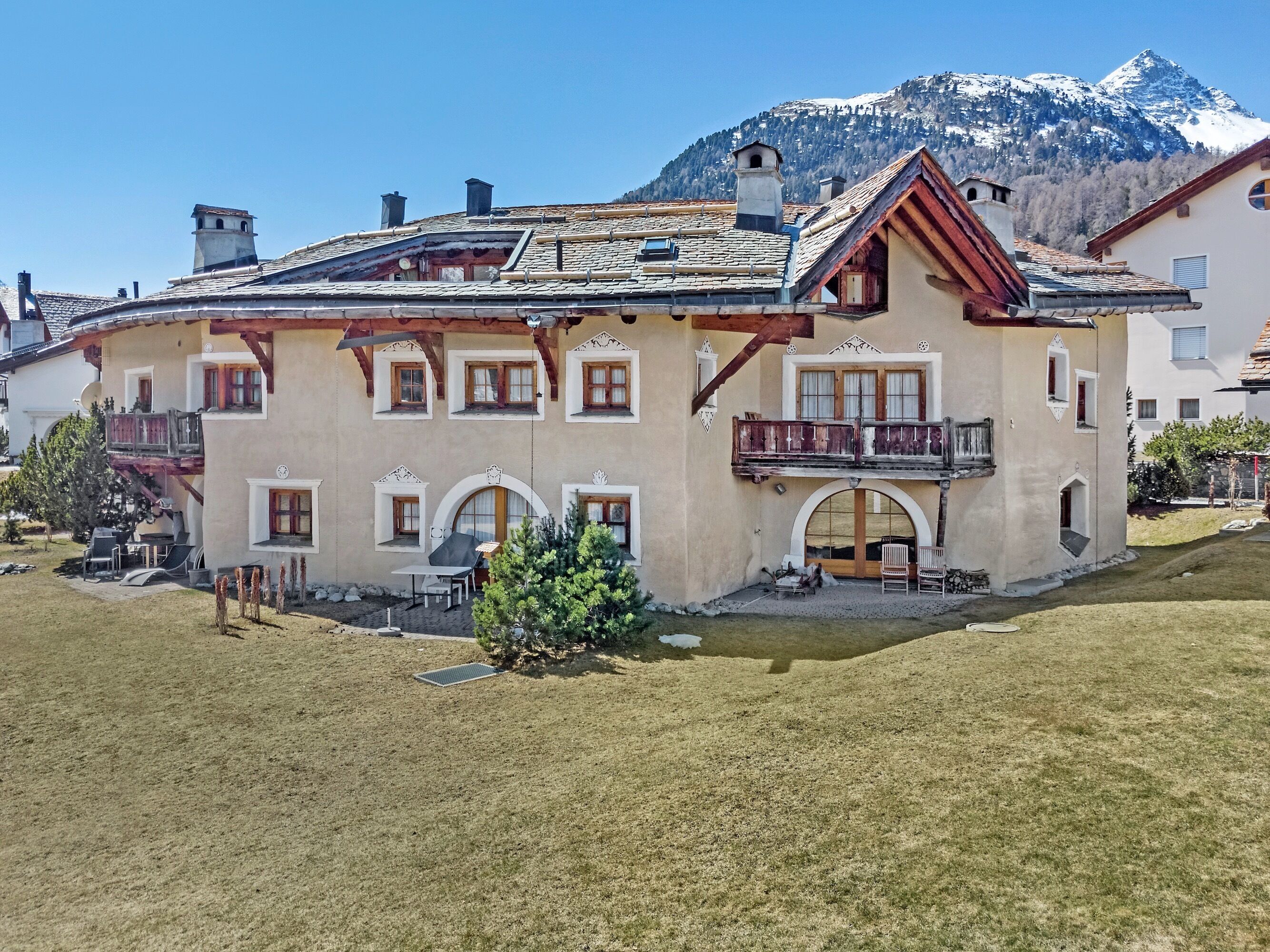 Un bâtiment à deux étages doté d’un balcon, avec une montagne en arrière-plan et un ciel dégagé.