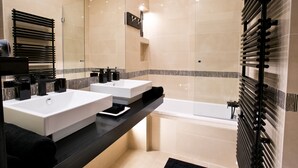Ein modernes Badezimmer mit zwei Waschbecken, einer Badewanne und einer Duschkabine aus Glas.