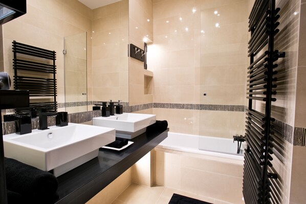 Une salle de bain moderne avec deux lavabos, une baignoire et une douche à l’italienne.