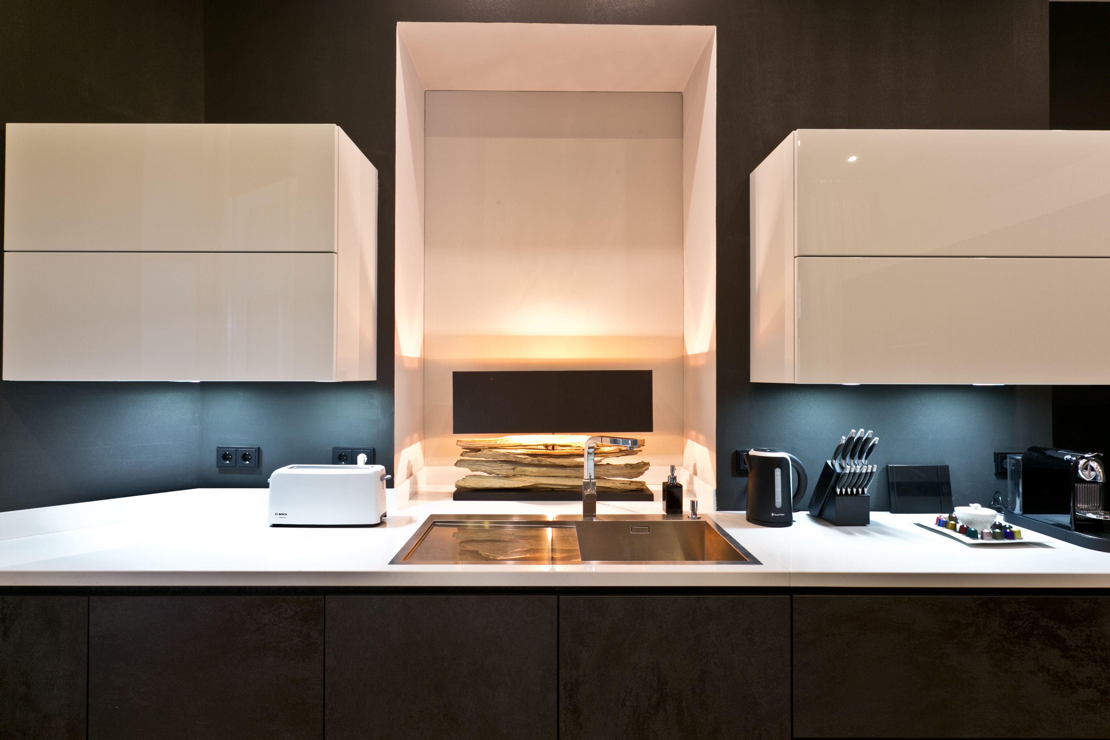 A modern kitchen with a central island, a Bosch toaster, a coffee machine, and a knife block.