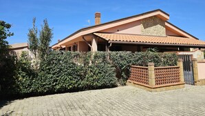 Una casa a due piani con tetto in tegole, un camino in pietra e un vialetto lastricato.