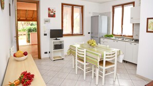 Una cucina compatta con mobili bianchi, un frigorifero, un lavello e un'area pranzo con tavolo e sedie.