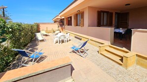 Un'area patio con tavolo e sedie, una piccola piscina e una scalinata che conduce a una zona coperta.