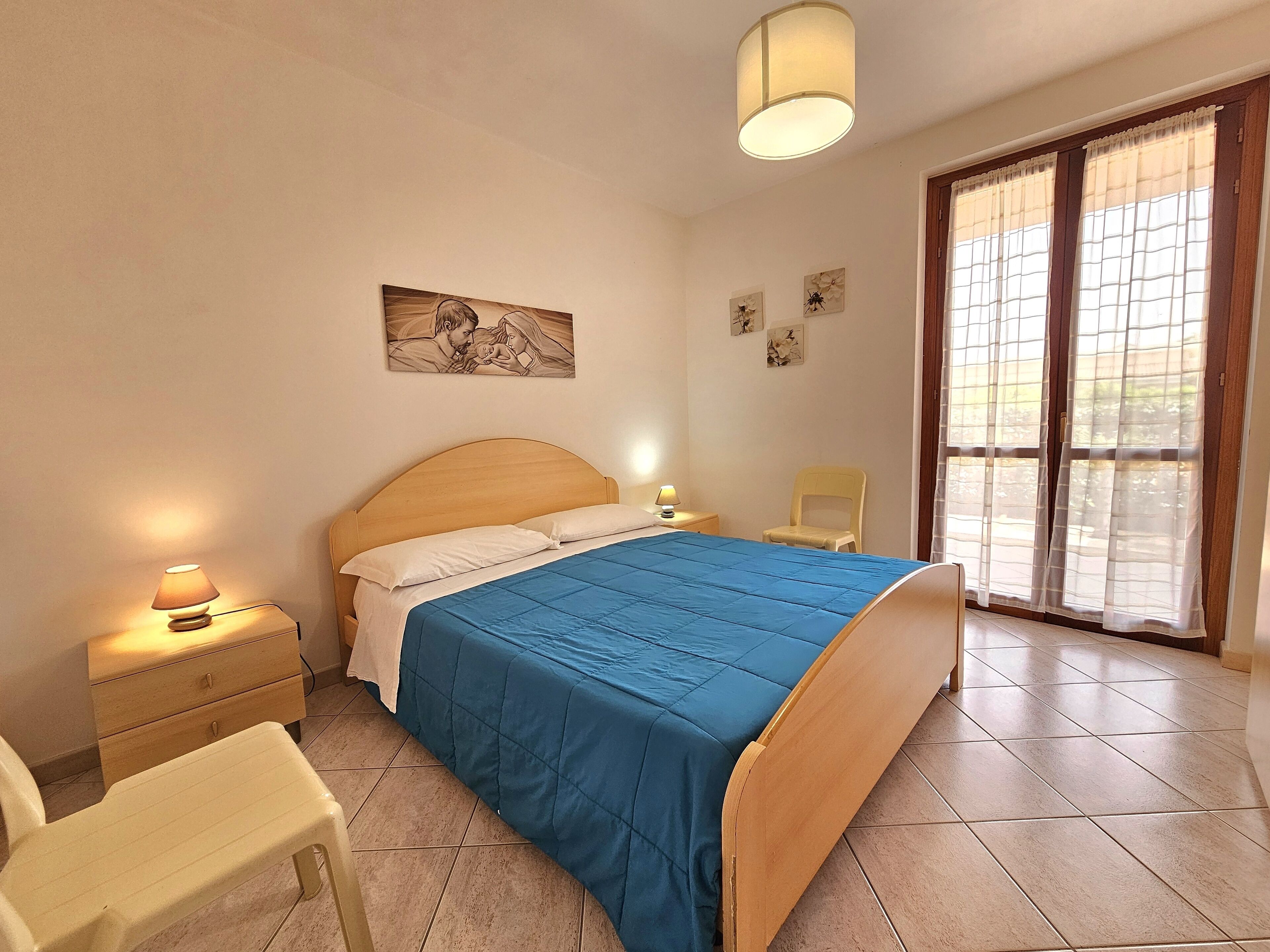A bedroom with a bed, bedside tables, a chair, and a window with curtains.