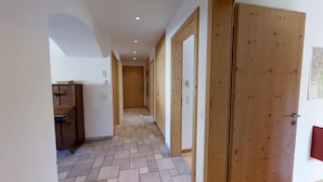 Un pasillo con puertas de madera, suelo de baldosas y un armario de madera.