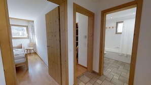 Una habitación con cama, una silla, una mesita y una ventana.