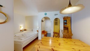 Una habitación con una cama, una mesa de madera, un espejo y un armario.