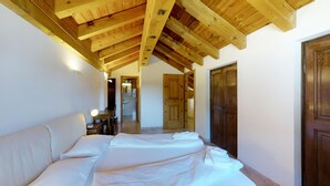 Une chambre avec un plafond en bois, un lit, une table de chevet avec une lampe et une porte donnant sur une salle de bain.
