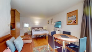 Ein Hotelzimmer mit Bett, Schreibtisch, Stuhl, Tisch, Fernseher und Fenster.