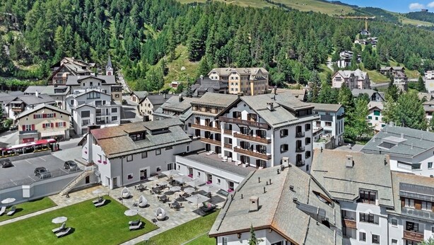 A mountain town with traditional architecture, including multi-story buildings with balconies and a central square with outdoor seating. - Studio apartment on the 3rd floor with balcony, approx. (Champfèr)