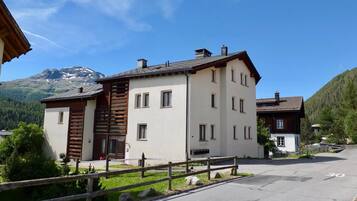 Ein zweistöckiges Gebäude mit Holzfassade und zahlreichen Fenstern, umgeben von einem Holzzaun und blauem Himmel.
