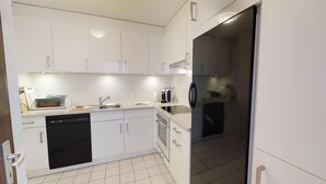 A modern kitchen with white cabinets, a dishwasher, a stove, and a refrigerator. - 4½-room apartment on the second floor, approx. (Celerina/Schlarigna)