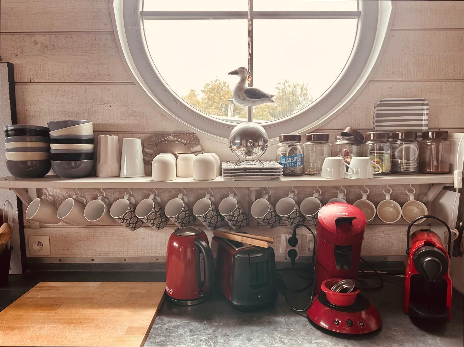 A kitchen with a window, various kitchenware, and appliances.