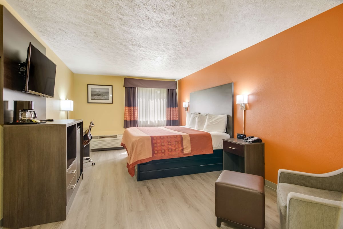 Ein Hotelzimmer mit Bett, Schreibtisch, Fernseher und Stuhl.