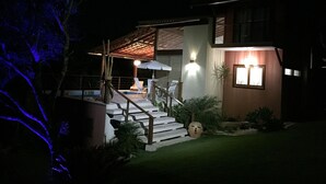 A modern house with a covered outdoor seating area and a staircase leading to the entrance.