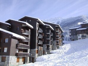 Una località montana innevata con edifici a più piani, balconi e facciate in pietra.