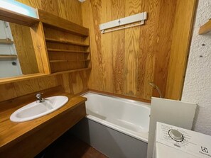Un bagno in legno con lavandino bianco, vasca da bagno e specchio.