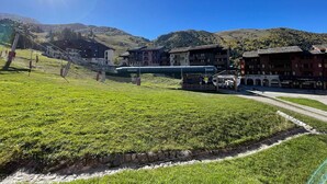 A ski resort with a cable car system, buildings, and a mountainous backdrop.
