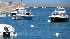 A harbor with several boats docked, a stone wall, and a lighthouse in the background. - HOLIDAY RENTAL HOUSE SAINT POL DE LEON (Saint-Pol-de-Léon)