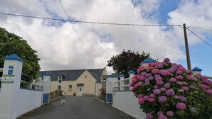 A gated driveway leading to a building with a white facade and blue accents. - HOLIDAY RENTAL HOUSE SAINT POL DE LEON (Saint-Pol-de-Léon)