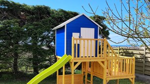A wooden playhouse with a blue exterior and a yellow slide. - HOLIDAY RENTAL HOUSE SAINT POL DE LEON (Saint-Pol-de-Léon)