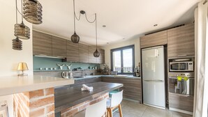 Een moderne keuken met een kookeiland van baksteen, roestvrijstalen apparatuur en hanglampen.