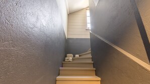Een smalle trap met beige treden die omhoog leiden, begrensd door donkere wanden.