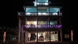 A multi-story building with a covered entrance and two cars parked inside.