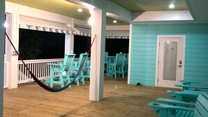 A covered outdoor area with turquoise chairs and a hammock.