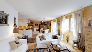 Una sala de estar acogedora con un sofá blanco, una mesita de centro y un comedor con una mesa y sillas de madera.