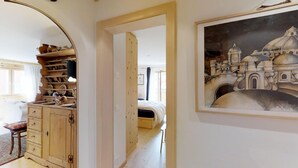 Una habitación con una cama, un aparador de madera y un cuadro de un edificio.