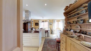 Una cocina amplia con armarios blancos, una isla central y un estante de madera con platos.