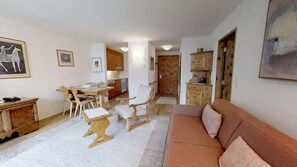 A cozy living room with a sofa, wooden furniture, and a dining area with chairs and a table.