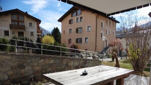An outdoor wooden table with a remote control, set against a stone wall and a clear sky. - 3-room apartment on the ground floor, about 90 m2. (Celerina/Schlarigna)