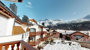 Un pueblo cubierto de nieve con edificios de estilo chalé, balcones de madera y una vista despejada de las montañas.