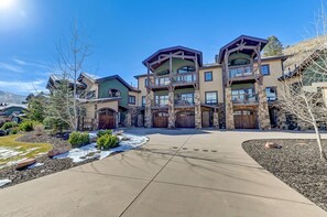 A multi-story residential building with a stone facade, multiple balconies, and a driveway leading to the entrance.