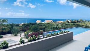 Ein Poolbereich mit Blick auf den Ozean und eine Wohngegend.