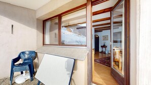 A room with a wooden-framed window, a whiteboard, a blue plastic chair, and a wooden floor.