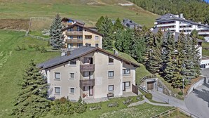 A multi-story hotel with balconies, surrounded by greenery and a mountain in the background.