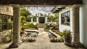 Ein Innenhof mit Steinsäulen, einem Pool und tropischen Pflanzen.