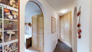 Un couloir avec des portes en bois, un lit à l’arrière-plan et un mur orné de tableaux encadrés.
