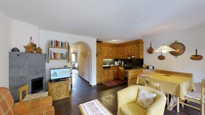 Un salon chaleureux avec une cheminée, un téléviseur et un coin repas comprenant une table et des chaises.