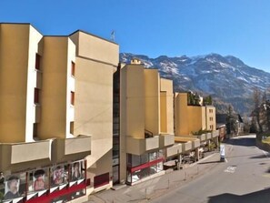 A row of modern buildings with a mountain backdrop. - Two-room apartment on the ground floor, 55m2. (St. Moritz)