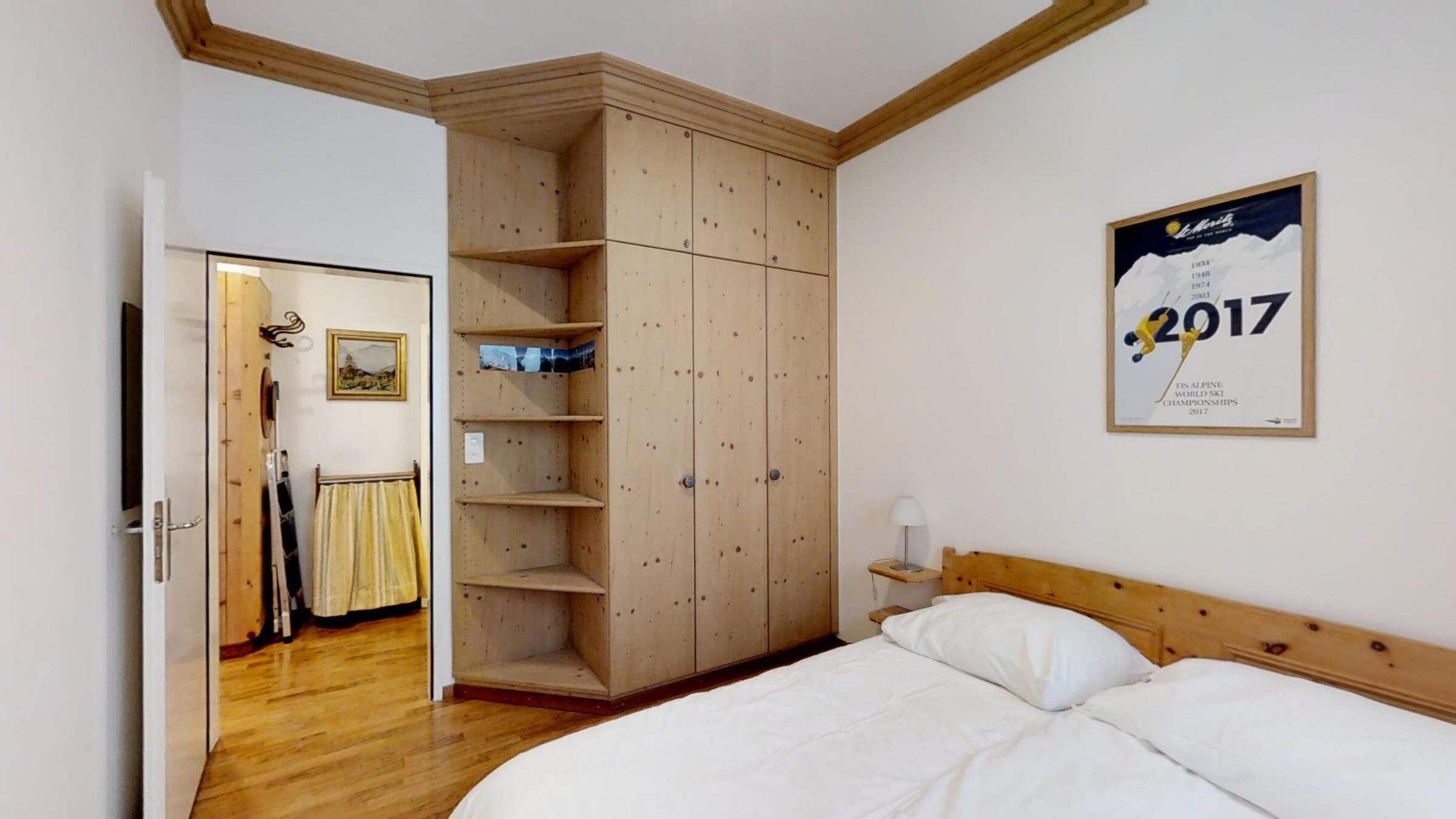 Ein Schlafzimmer mit einem hölzernen Bett, einem Kleiderschrank und einem Poster an der Wand.