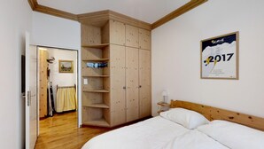 Ein Schlafzimmer mit einem hölzernen Bett, einem Kleiderschrank und einem Poster an der Wand.