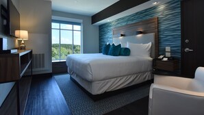Habitación de hotel moderna con una cama grande, un escritorio, una silla y vistas al exterior.