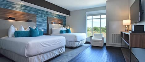 A modern hotel room with two beds, a seating area, a TV, and a large window offering a view.